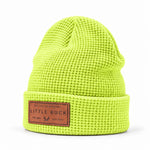 A bright neon yellow-green waffle-knit beanie hat with a brown leather patch on the front cuff reading 'LITTLE BUCK'.