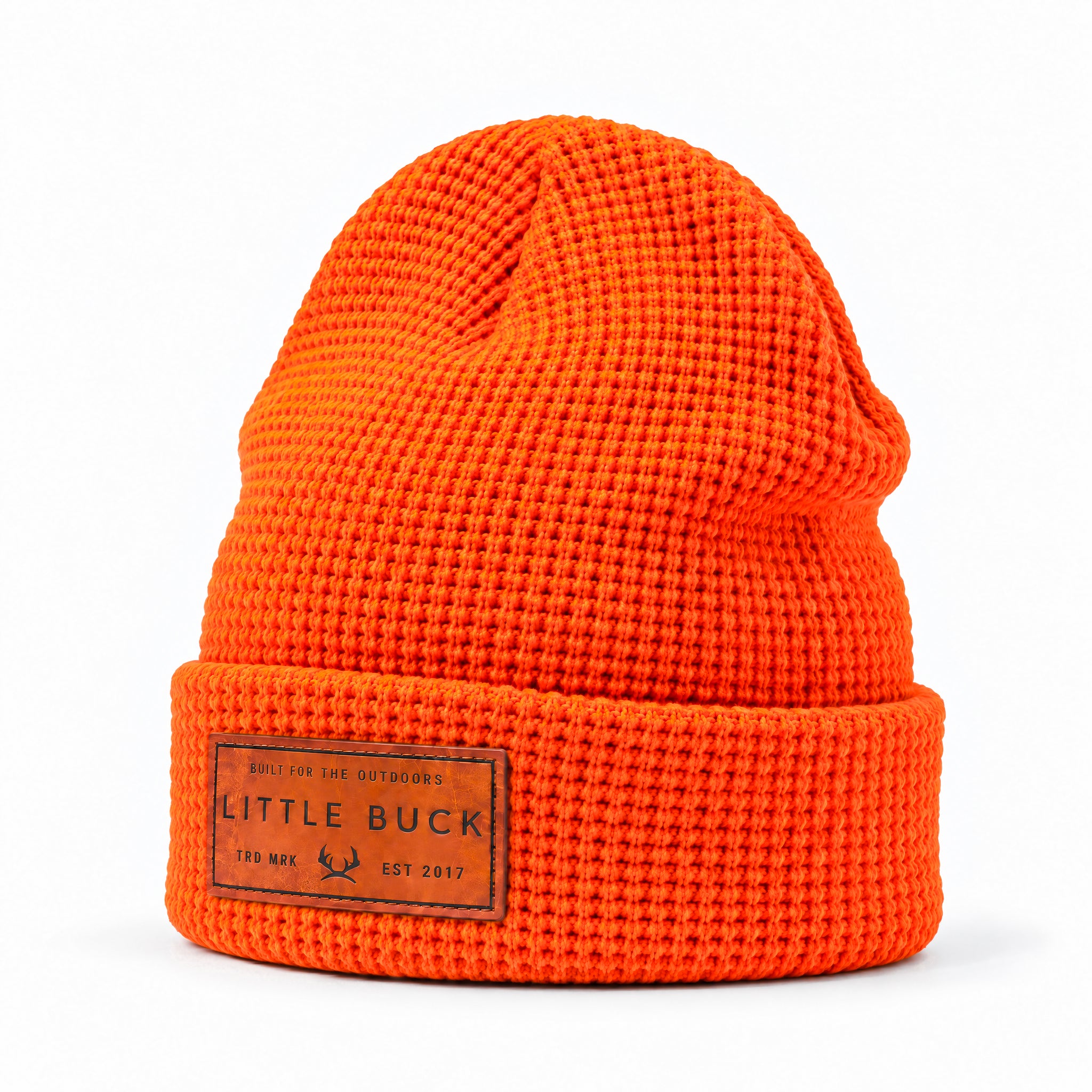 Bright orange waffle-knit beanie hat with a folded cuff and a brown rectangular leather patch reading LITTLE BUCK on a white background.